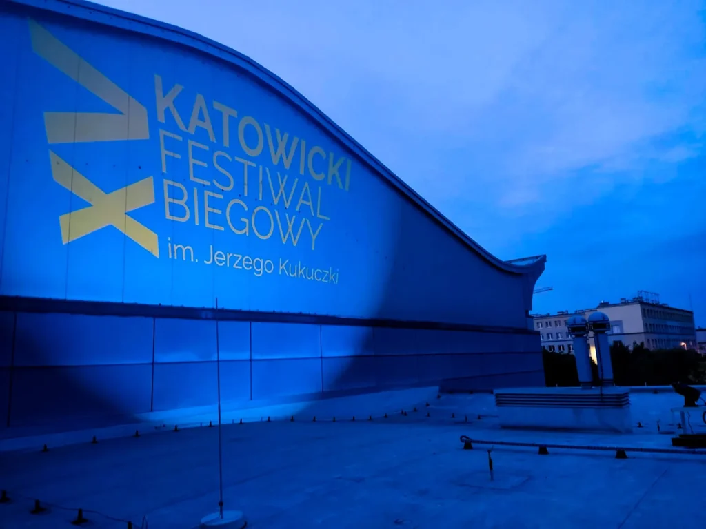 Projekcja GOBO z grafiką Katowickiego Festiwalu Biegowego na elewacji obiektu w Katowicach po zmroku