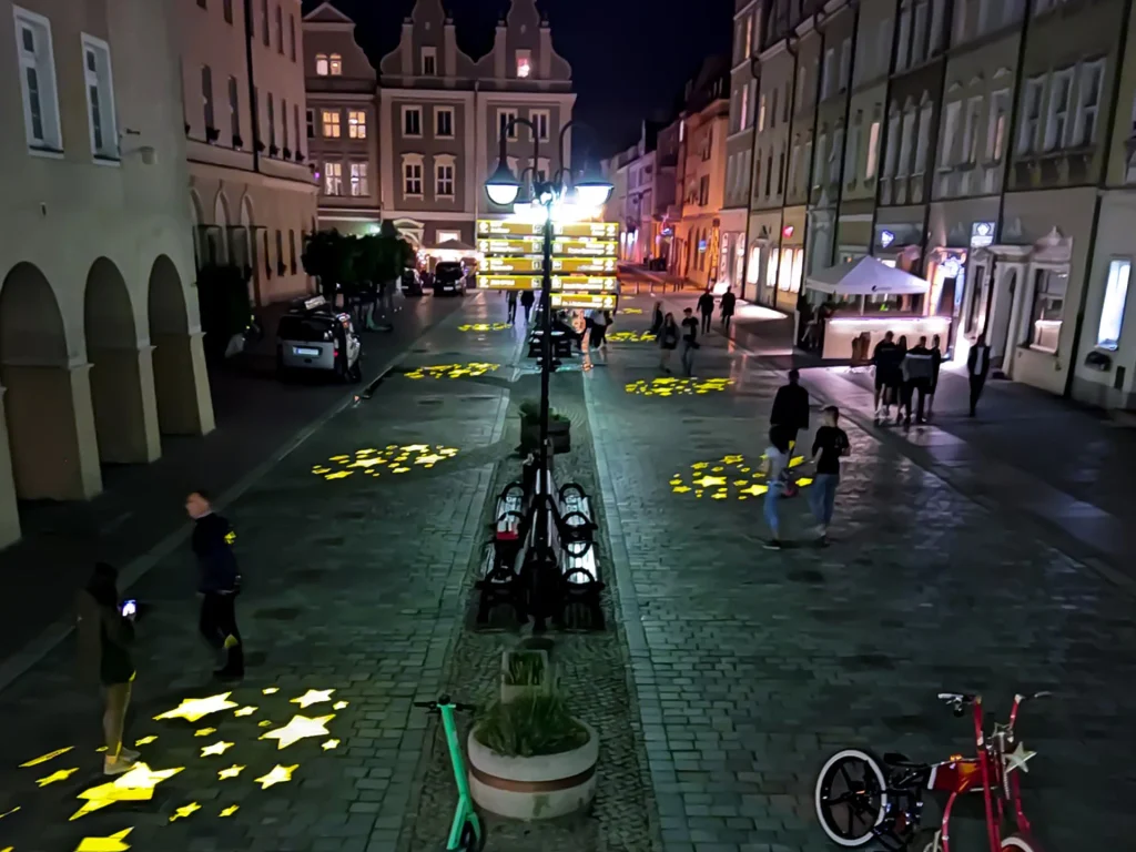 Swietlne znaki GOBO na bruku deptaka w centrum miasta po zmroku